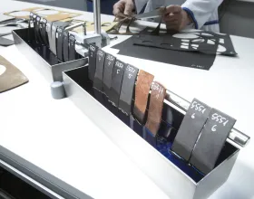 Plusieurs échantillons de cuir trempés dans un liquide coloré, à l’arrière-plan un homme examine d’autres échantillons.