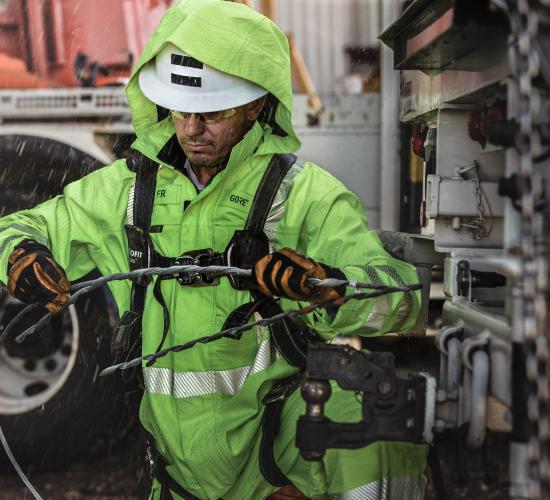an electrical utility worker in hi-vis gear working under the rain